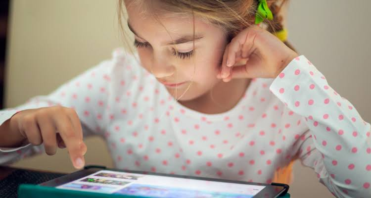 A CHILD LOOKING AT HER TAB