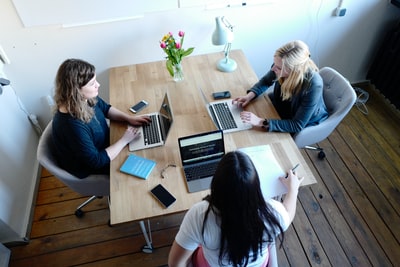 Three ladies sitting around a table with laptop - Paypant.com
