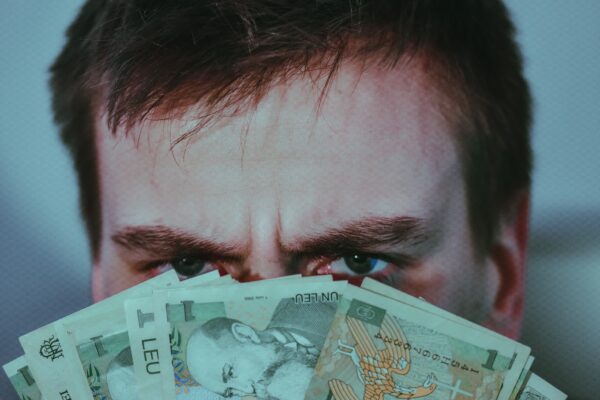 A man covering his face with some cash